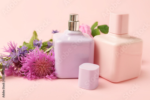 Bottles of floral perfume on color background
