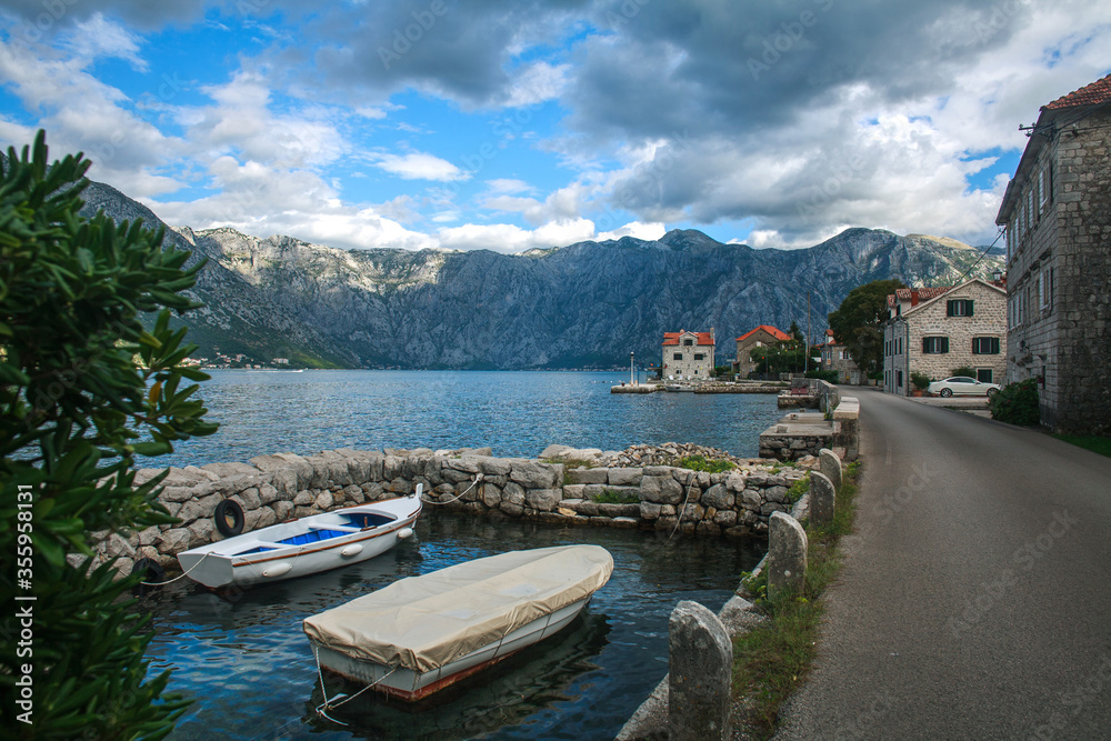 Old town settlement around lake, Kotor Bay, on background of blue sky and clouds, Montenegro, Europe