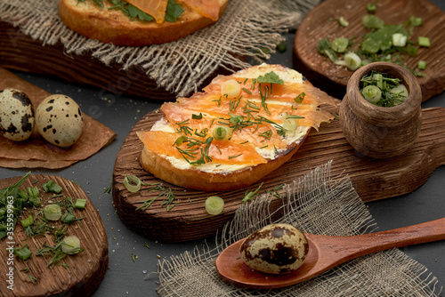 Cheese and trout sandwich on a wooden Board. Diet Breakfast sandwich with red fish, quail eggs and greens.