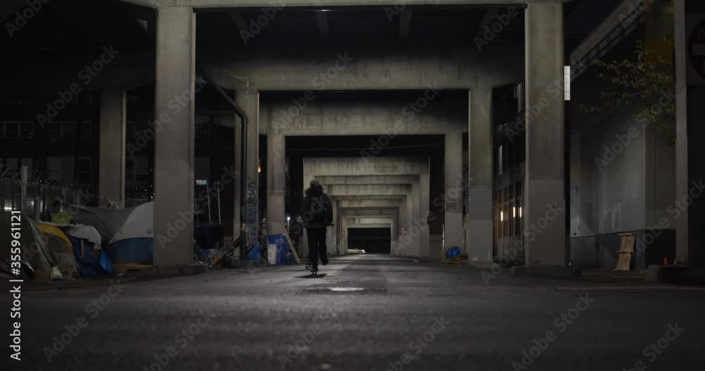 Two skaters ride under an overpass at night. Two skaters ride under an overpass at night.