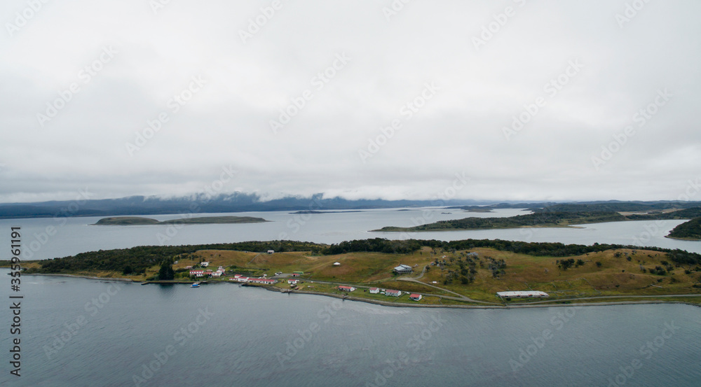 Panorama aerial view of the Beagle Channel in Ushuaia, Tierra del Fuego, Patagonia Argentina. The ocean bay, sea water, coastline, field and rural residences in a cloudy day.