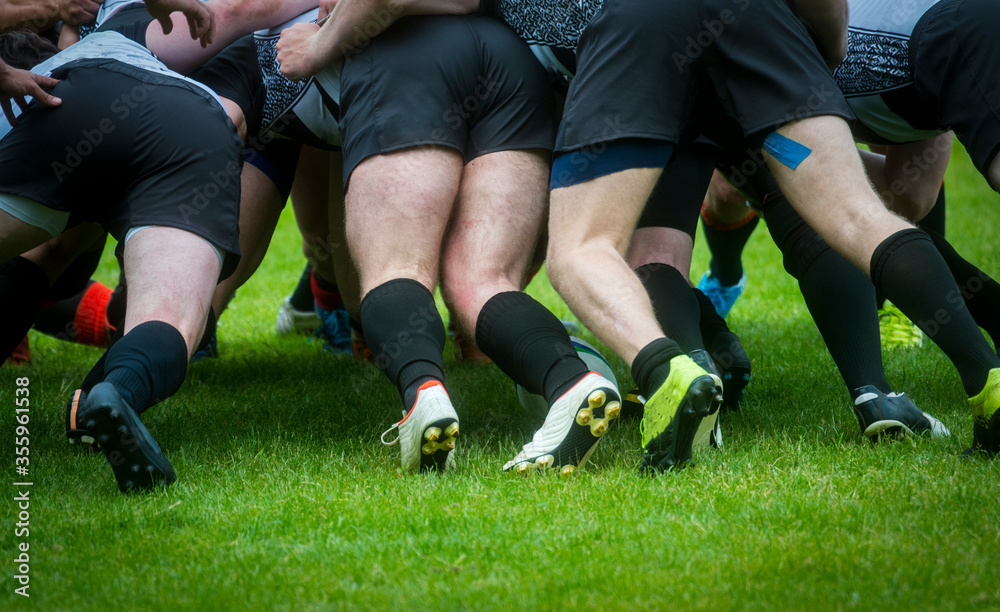 Low Section Of People Playing Rugby On Grassy Field. Rugby players in scrum. Team sport. Low Section Of People Playing Rugby On Grassy Field. Rugby players in scrum. Team sport.