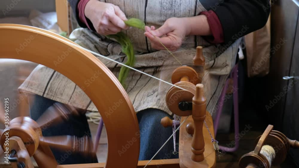 Frau spinnt aus Wolle Garn am Spinnrad