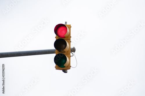 A red traffic light stop light / trafficlight stoplight isolated with a sky background backdrop signaling to stop