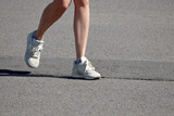Slim girl running on a street, female legs in sneakers. Concept of workout, woman runner, slimming in summer season