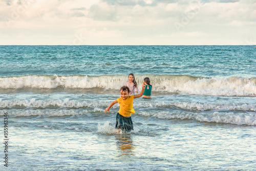 Children running in the water on the beach on a beautiful day © Rogerio