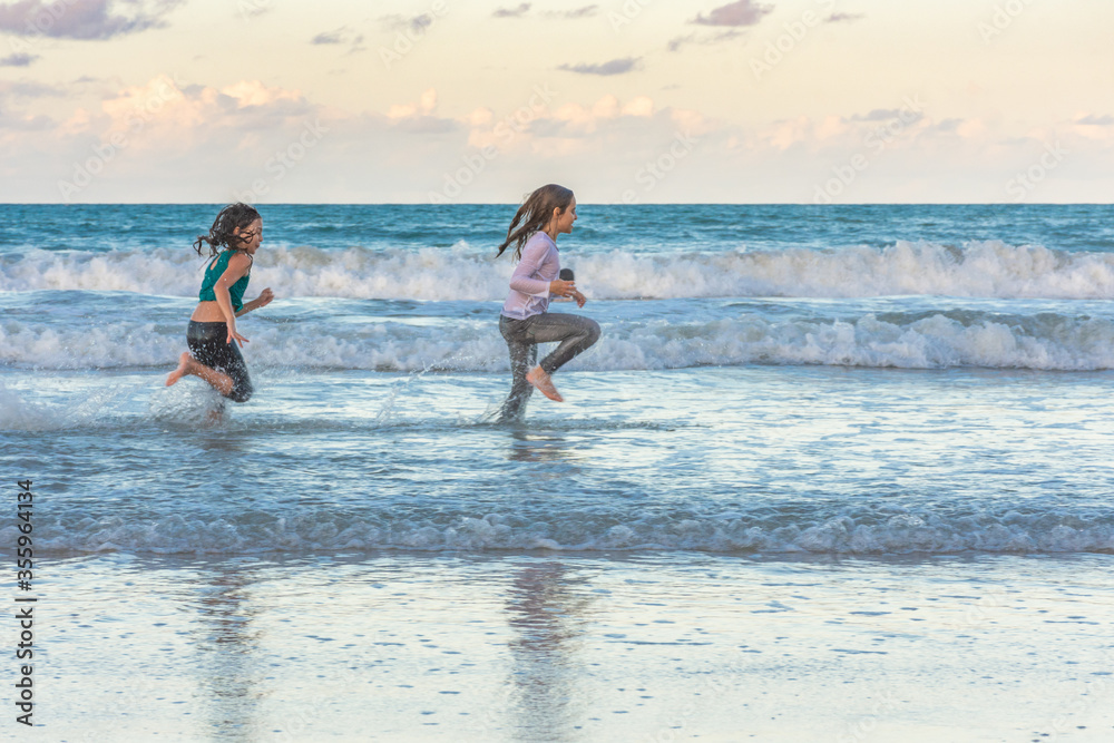 Children running on the beach juggling joy
