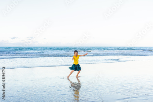 Child dancing cheerfully on the beach with shadows