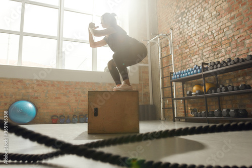 Delivering good health. Sportive woman using plyo box while having workout at industrial gym photo