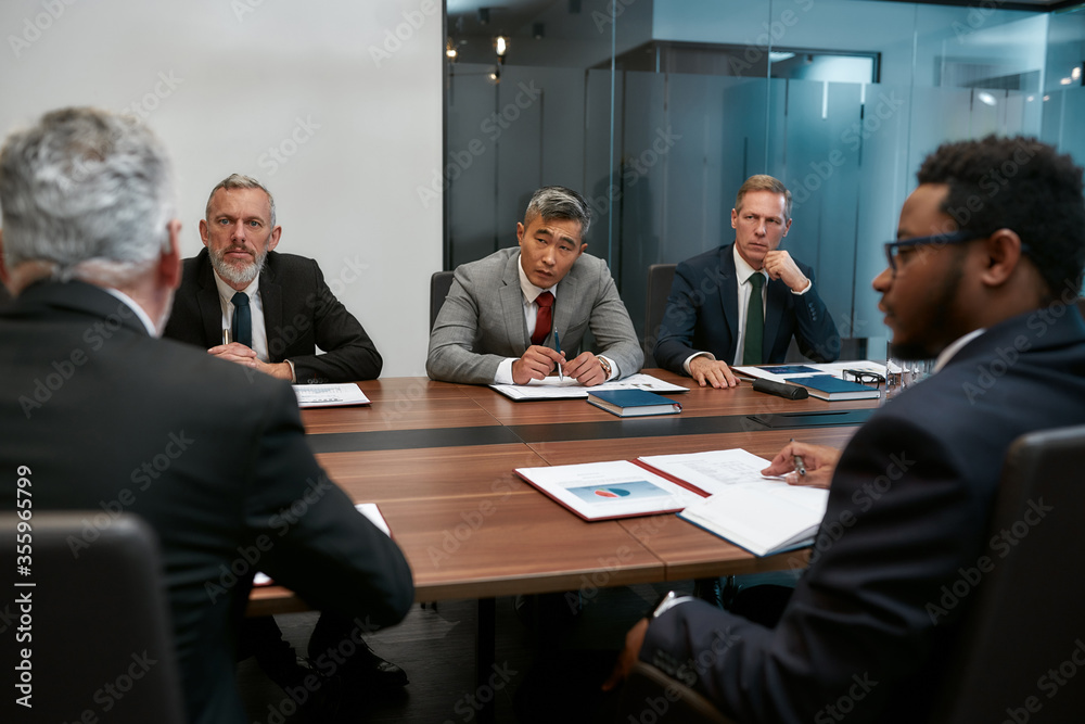 Serious issue. Five multicultural business people in formal wear discussing having a meeting in the modern office