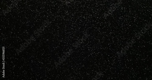 Silver glitter background. 4K abstract motion background of shining silver particles shimmering against black space. Glistening star effect. Black minimalist design.