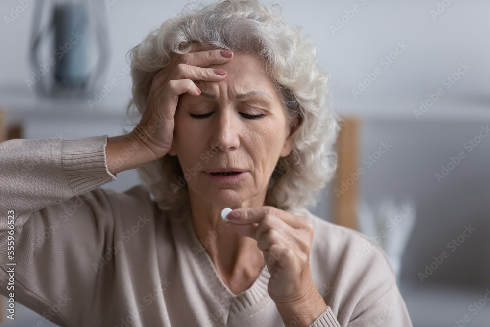Tired senior woman touch head suffer from migraine or headache have antibiotic or aspirin pill at home, exhausted mature female take meds struggle with high blood pressure, elderly healthcare concept Tired senior woman touch head suffer from migraine or headache have antibiotic or aspirin pill at home, exhausted mature female take meds struggle with high blood pressure, elderly healthcare concept
