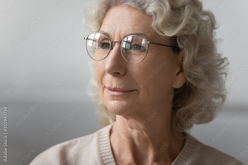 Close up of senior 50s woman in glasses look in distance thinking or pondering, mature 60s female wear modern round spectacles after optician consultation in clinic, eyesight problem, eyewear concept
