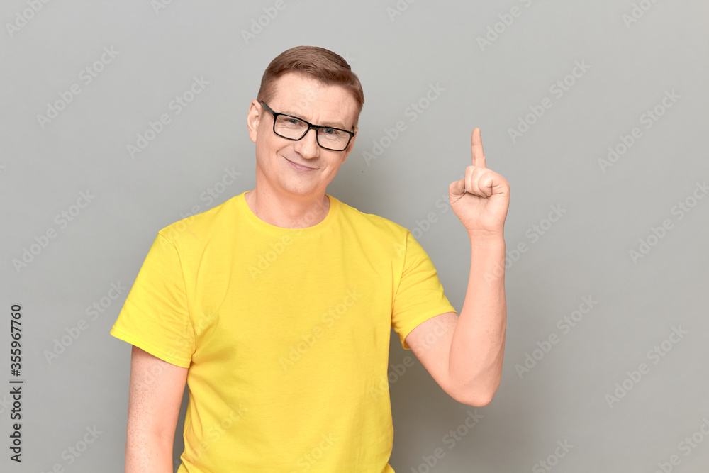 Portrait of happy man raising index finger up and making notice