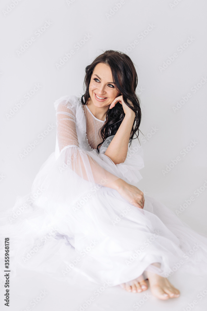 A beautiful and lovely brunette girl with perfect smooth skin and incredible brown eyes in a luxurious white dress smiles a bright and snowy smile. Light and airy vertical photo A beautiful and lovely brunette girl with perfect smooth skin and incredible brown eyes in a luxurious white dress smiles a bright and snowy smile. Light and airy vertical photo