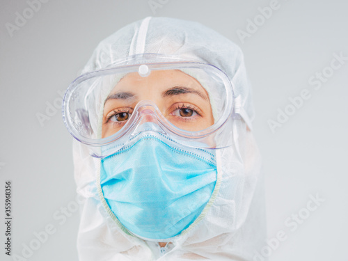 Portrait of a caucasian female doctor wearing ppe suit, mask and glasses in hospital.