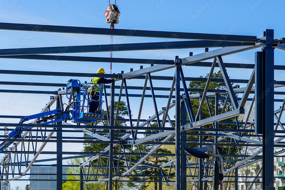 assembly of the metal frame of a new building with the use of a crane and scissor lift assembly of the metal frame of a new building with the use of a crane and scissor lift