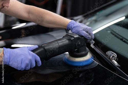 Car detailing studio worker polishing car paint