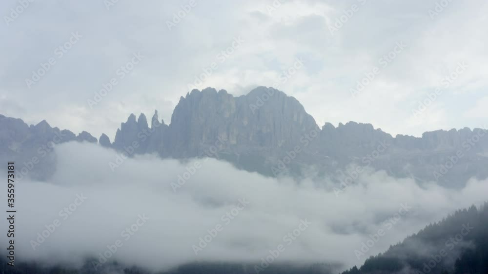 Aerial shot of rocky mountains amidst clouds against sky, drone flying backward over landscape - Dolomites, Italy Aerial shot of rocky mountains amidst clouds against sky, drone flying backward over landscape - Dolomites, Italy