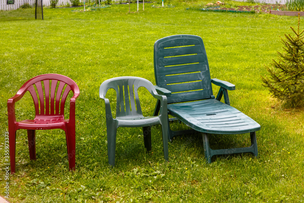 Wet plastic chairs stand on the green grass after the rain. Wet plastic chairs stand on the green grass after the rain.