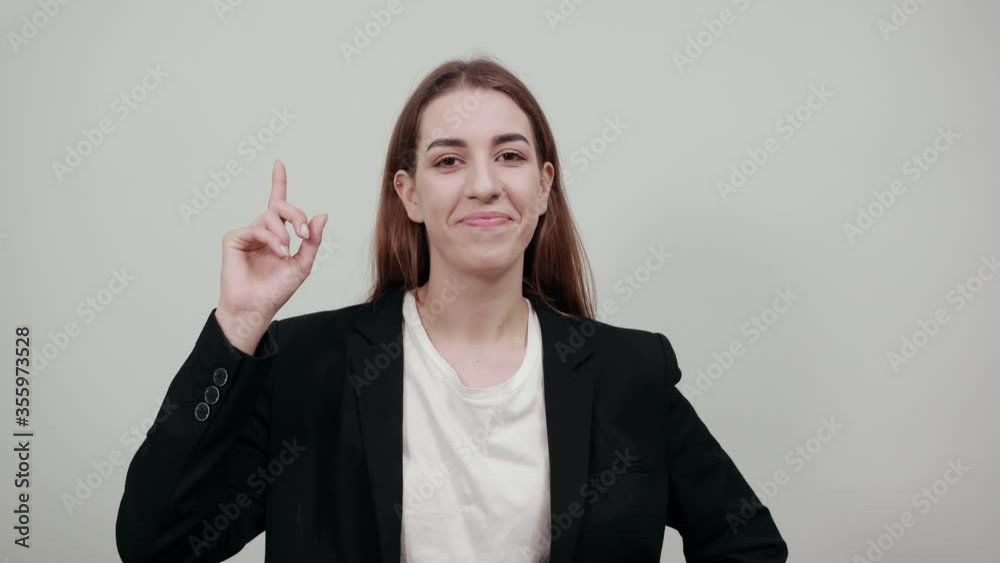 Hand points index finger up, pointing forefinger surprise gift option, great idea. Young attractive woman with brown hair in a light t-shirt and black jacket on white background Hand points index finger up, pointing forefinger surprise gift option, great idea. Young attractive woman with brown hair in a light t-shirt and black jacket on white background