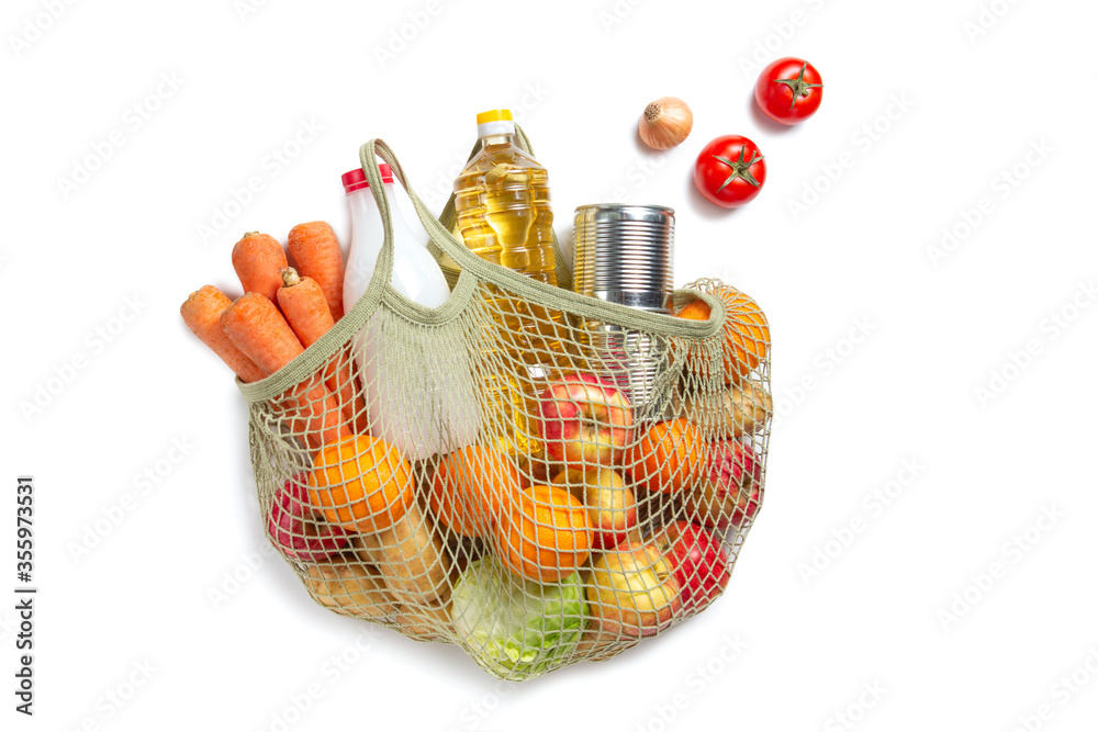 Vegetables, fruits, sunflower oil and milk in a string bag on a white isolated background. Flat lay. The concept of green shopping and proper nutrition. Environmental Protection. Delivery of products.