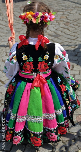 the girl in a traditional folk dress from Lowicz in Poland, while joins Corpus Christi procession in street