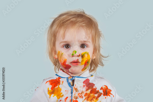 Children's pranks. He looks surprised. A baby painted his face, hands and clothes.