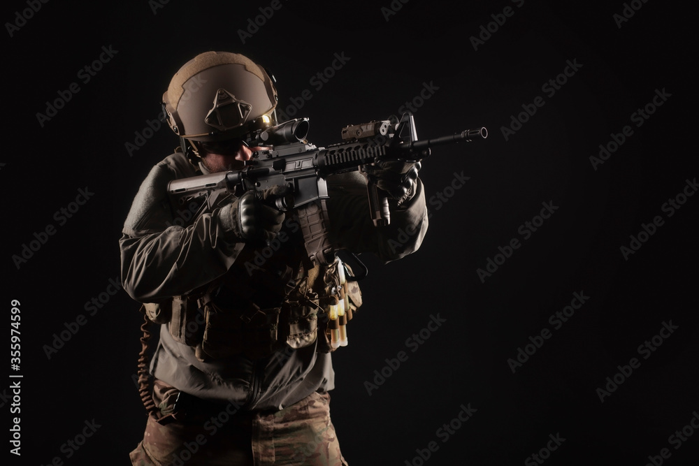 American special forces against a dark background, a soldier in military equipment holds weapons and takes aim, elite troops