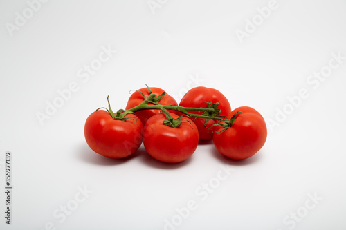 Close up shot of a bunch of fresh red organic tomatoes isolated on white background with copy space
