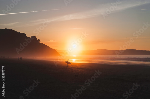 Surfer and the sunset on the beach in Asturias, Spain