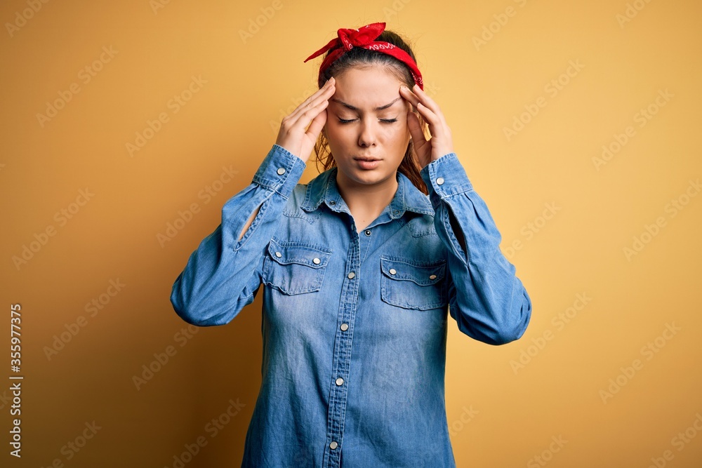 Young beautiful brunette woman wearing casual denim shirt and hair handkerchief with hand on head for pain in head because stress. Suffering migraine. Young beautiful brunette woman wearing casual denim shirt and hair handkerchief with hand on head for pain in head because stress. Suffering migraine.