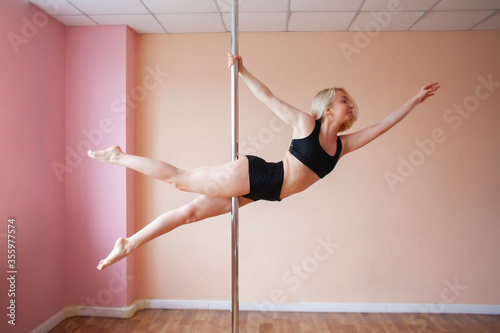 pole dance training, girl hanging on a pylon and doing gymnastics, a sport for girls