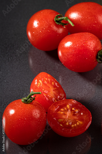 A portion of tasteful red tomatoes on a dark background. Fresh, delicious and red tomatoes, with drops of water on a dark background. photo