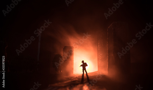 Empty street of burnt up city, flames on the ground and blasts with smoke in the distance. Apocalyptic view of city downtown as disaster film poster concept. Night scene. City destroyed by war.