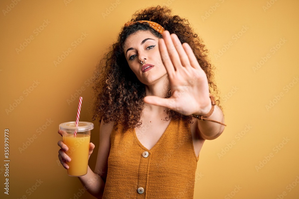 Εκτύπωση καμβά Young beautiful woman with curly hair and piercing drinking healthy orange juice