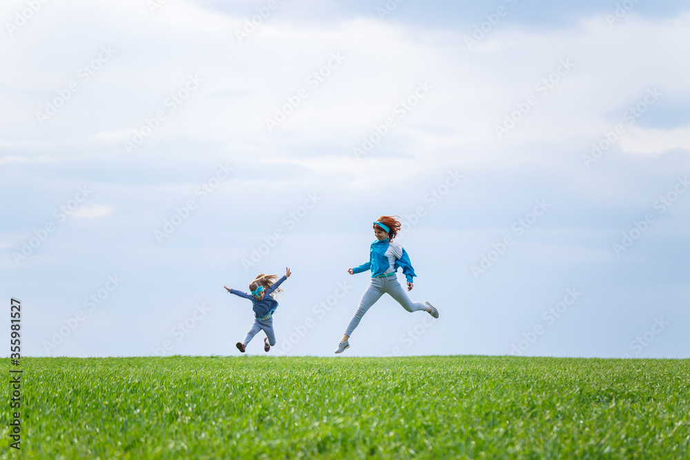 little girl child and mother woman run and jump, green grass in the field, sunny spring weather, smile and joy of the child, blue sky with clouds little girl child and mother woman run and jump, green grass in the field, sunny spring weather, smile and joy of the child, blue sky with clouds
