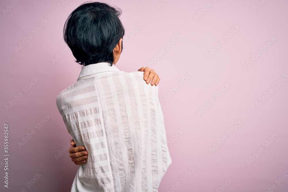 Young beautiful asian girl wearing casual shirt standing over isolated pink background Hugging oneself happy and positive from backwards. Self love and self care