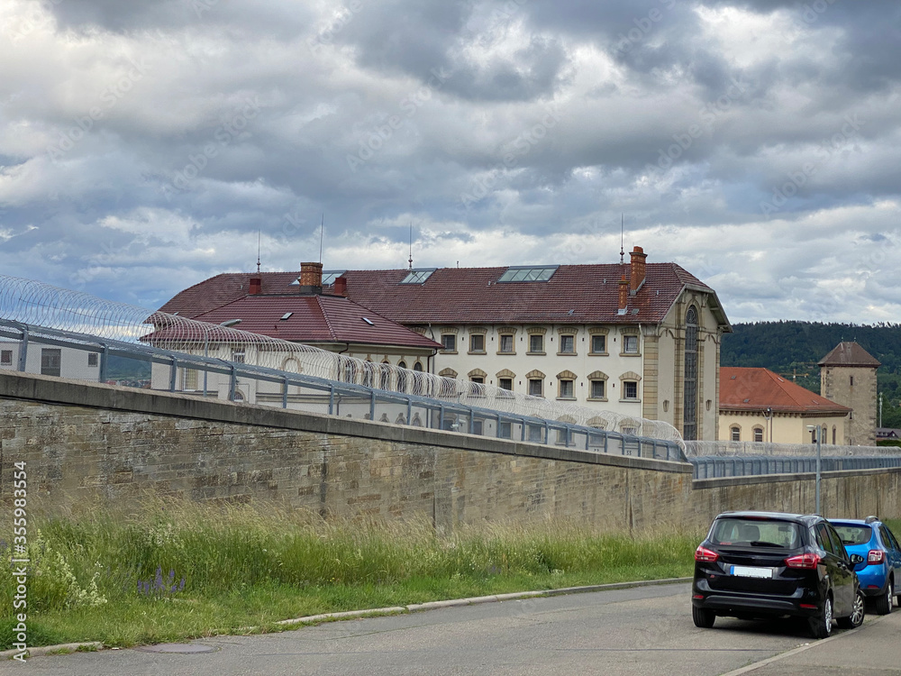 Gefängnis mit hoher Mauer neben parkenden Autos
