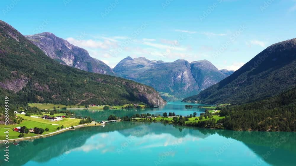 Aerial view on a blue lake with some houses on the beach. Landscape with a drone. Blue lakes, islands, and green forests from above on a cloudy summer morning 