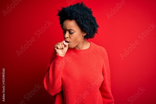 Young beautiful African American afro woman with curly hair wearing casual sweater feeling unwell and coughing as symptom for cold or bronchitis. Health care concept.
