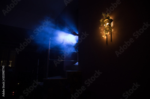 Horror concept. Scary mask with light on the wall inside dark room. Selective focus