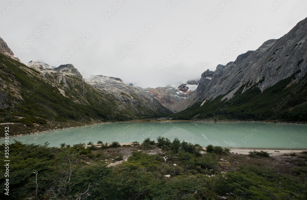 Panorama view of glacier water Emerald Lake i9n the mountaintop, in Ushuaia, Tierra del Fuego Patagonia Argentina. Turquoise color water lake surrounded by the Andes mountains and forest.