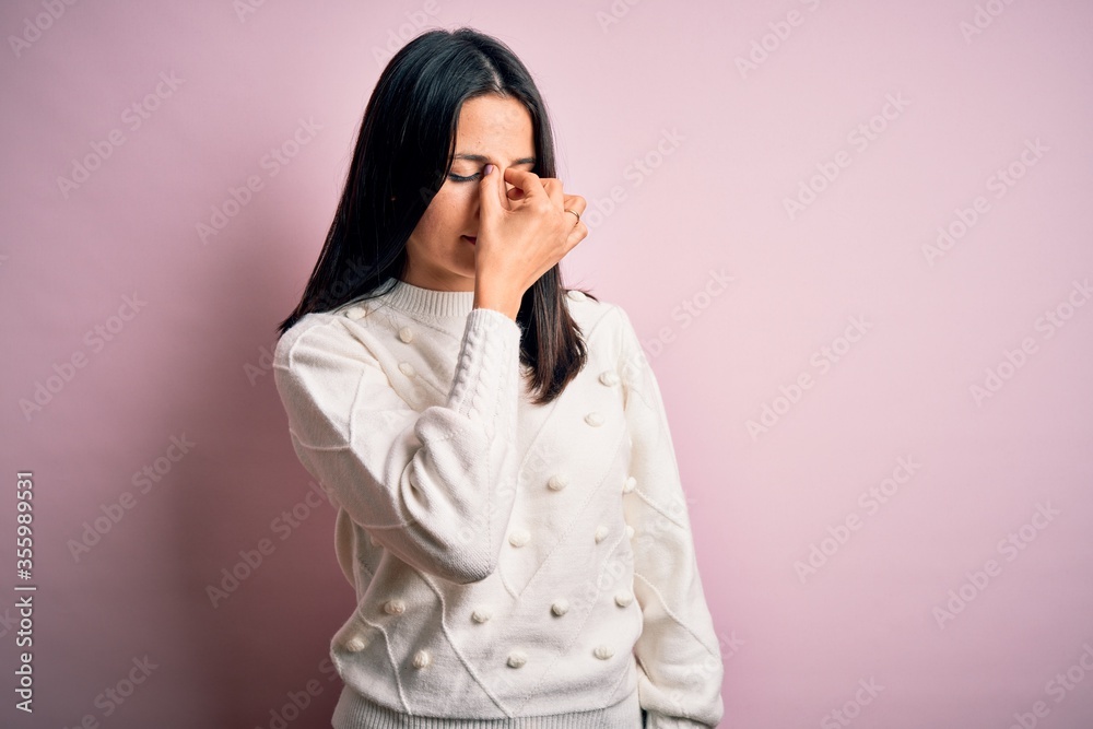 Young brunette woman with blue eyes wearing casual sweater over isolated pink background tired rubbing nose and eyes feeling fatigue and headache. Stress and frustration concept. Young brunette woman with blue eyes wearing casual sweater over isolated pink background tired rubbing nose and eyes feeling fatigue and headache. Stress and frustration concept.