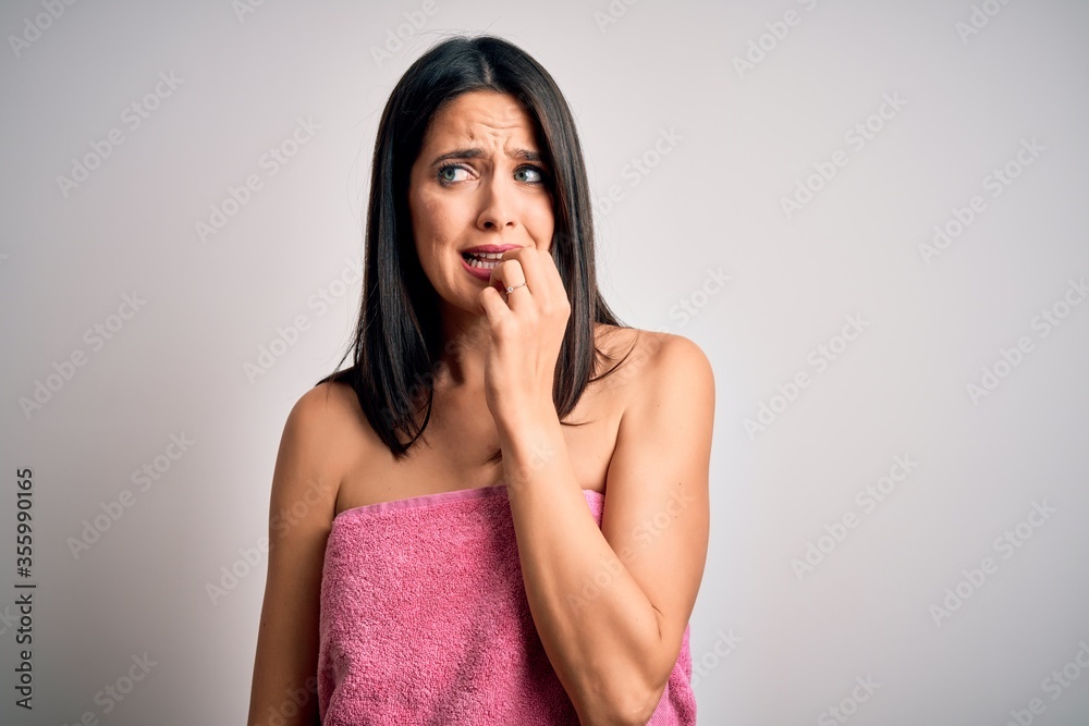 Young brunette woman with blue eyes wearing shower towel after bath over white background looking stressed and nervous with hands on mouth biting nails. Anxiety problem. Young brunette woman with blue eyes wearing shower towel after bath over white background looking stressed and nervous with hands on mouth biting nails. Anxiety problem.