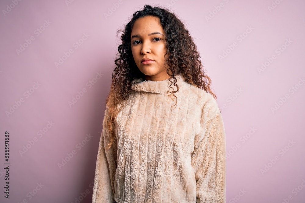 Young beautiful woman with curly hair wearing casual sweater standing over pink background Relaxed with serious expression on face. Simple and natural looking at the camera. Young beautiful woman with curly hair wearing casual sweater standing over pink background Relaxed with serious expression on face. Simple and natural looking at the camera.