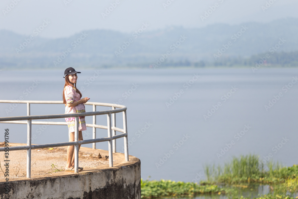 young pregnant woman standing on a pier at the lake in mountain side during beautiful sunny day in summer season young pregnant woman standing on a pier at the lake in mountain side during beautiful sunny day in summer season