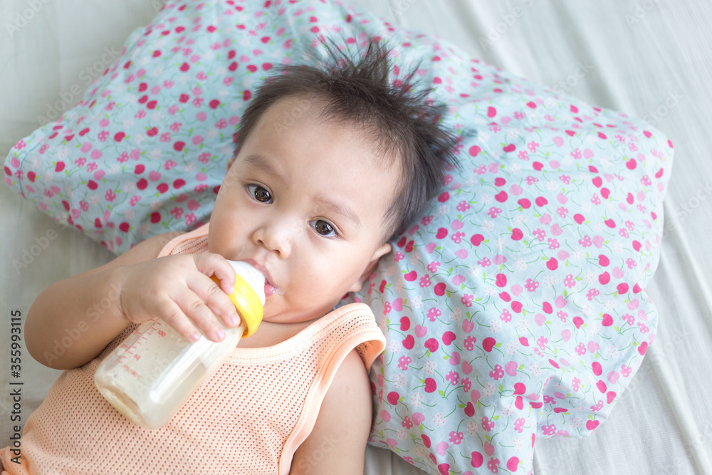 Cute little newborn baby boy drinking milk from milk bottle on the bed Cute little newborn baby boy drinking milk from milk bottle on the bed