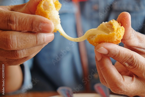 Woman's hand holding fried mozzarella cheese ball 