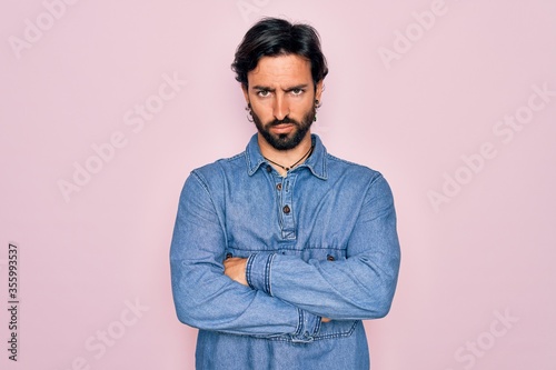Young handsome hispanic bohemian man wearing hippie style over pink background skeptic and nervous, disapproving expression on face with crossed arms. Negative person. © Krakenimages.com